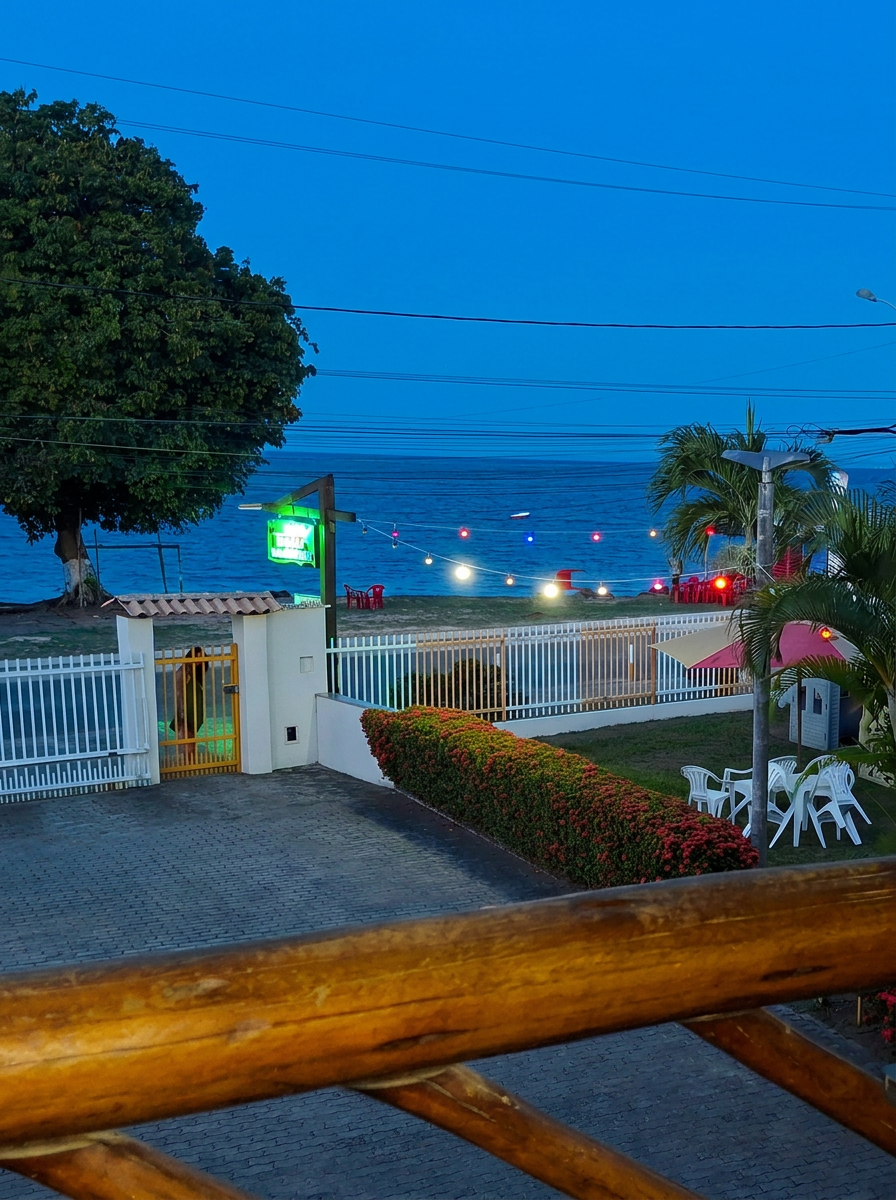 Vista do mar ao entardecer com luzes coloridas do bistrô